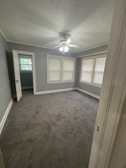 2120 68th Ter, Kansas City, MO 64132 - unfurnished bedroom with a ceiling fan, a textured ceiling, baseboards, ornamental molding, and dark carpet