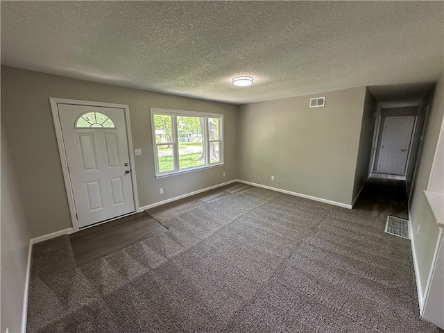 carpeted foyer entrance with visible vents, a textured ceiling, and baseboards