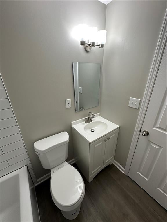 full bathroom with vanity, wood finished floors, toilet, and a washtub