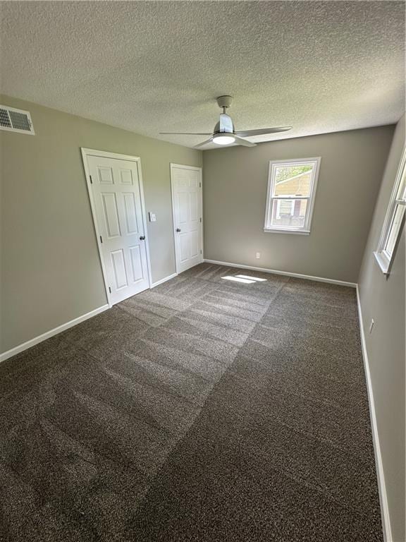 unfurnished bedroom featuring ceiling fan, carpet floors, a textured ceiling, baseboards, and visible vents