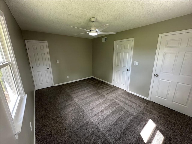 unfurnished bedroom with baseboards, carpet flooring, a textured ceiling, and visible vents