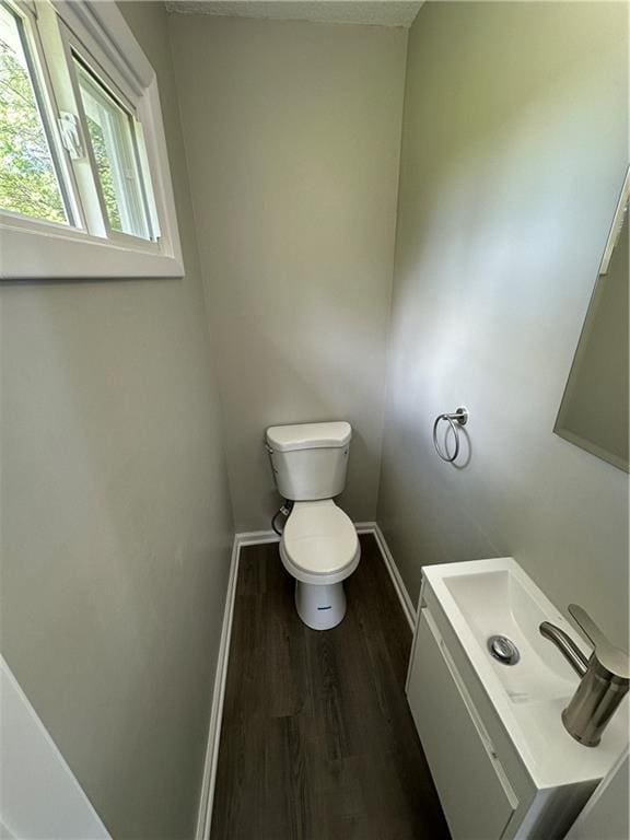 half bathroom featuring baseboards, vanity, toilet, and wood finished floors