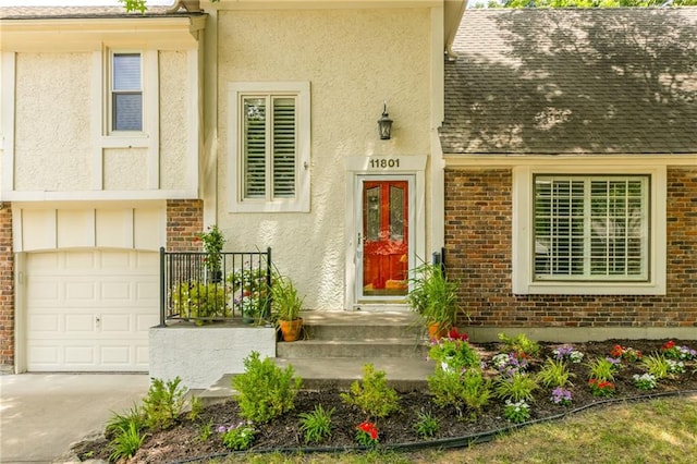 11801 Avila Dr, Kansas City, MO 64114 - view of exterior entry featuring brick siding, an attached garage, a shingled roof, and stucco siding