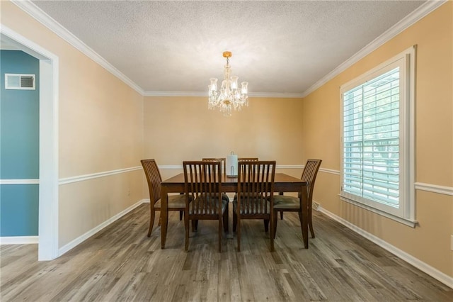 11801 Avila Dr, Kansas City, MO 64114 - dining space with healthy amount of natural light, a textured ceiling, wood finished floors, ornamental molding, and a chandelier