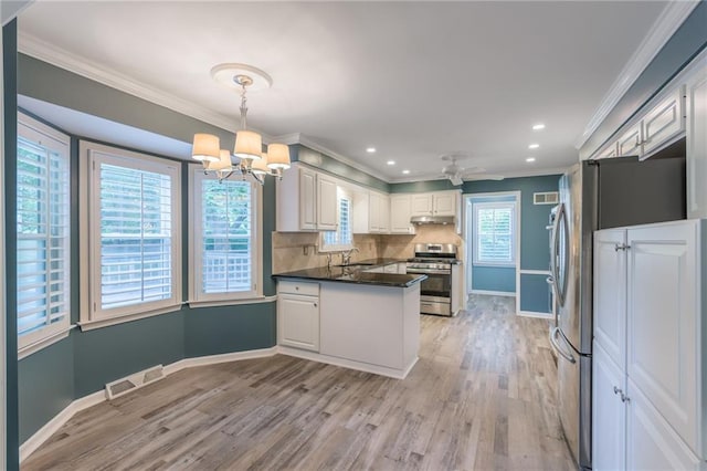 11801 Avila Dr, Kansas City, MO 64114 - kitchen with stainless steel gas stove, a peninsula, under cabinet range hood, dark countertops, and a chandelier