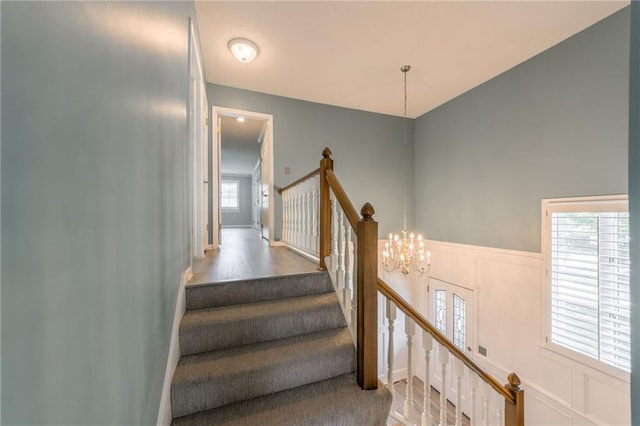 11801 Avila Dr, Kansas City, MO 64114 - staircase with a chandelier, a decorative wall, a wainscoted wall, and wood finished floors