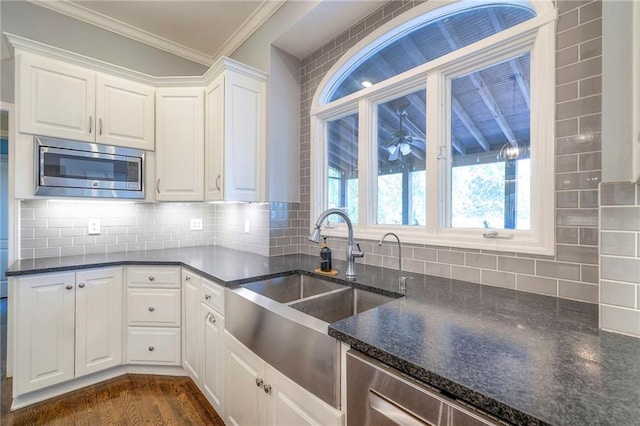 5701 W 148th Pl, Overland Park, KS 66223 - kitchen with stainless steel microwave, ornamental molding, white cabinets, dark stone countertops, and tasteful backsplash