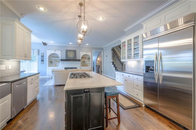 5701 W 148th Pl, Overland Park, KS 66223 - kitchen featuring stainless steel appliances, white cabinets, a breakfast bar area, glass insert cabinets, and dark wood finished floors