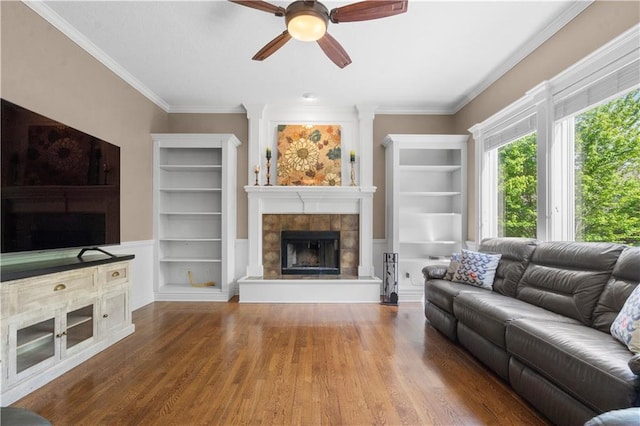 7406 W 145th Ter, Overland Park, KS 66223 - living room with a tiled fireplace, ceiling fan, wood finished floors, crown molding, and built in features