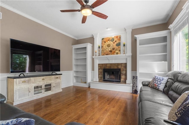 7406 W 145th Ter, Overland Park, KS 66223 - living area with wood finished floors, ceiling fan, crown molding, a tile fireplace, and built in shelves