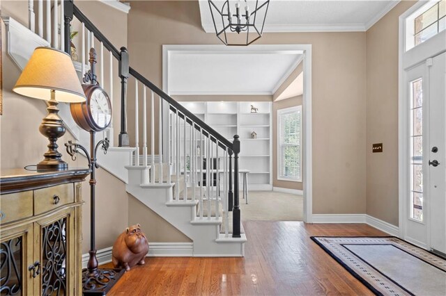 7406 W 145th Ter, Overland Park, KS 66223 - entryway with plenty of natural light, a chandelier, wood finished floors, stairway, and crown molding
