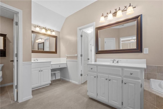 7406 W 145th Ter, Overland Park, KS 66223 - bathroom with two vanities, a relaxing tiled tub, vaulted ceiling, and baseboards