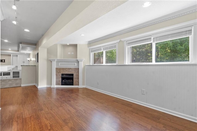 7406 W 145th Ter, Overland Park, KS 66223 - unfurnished living room featuring wood finished floors, a tile fireplace, baseboards, wainscoting, and rail lighting
