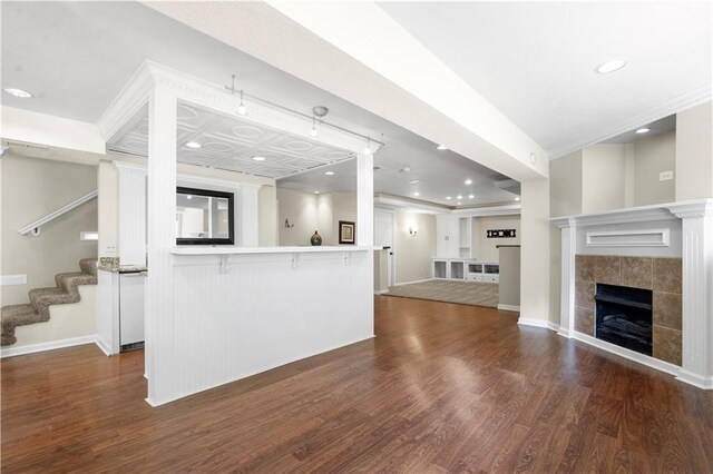 7406 W 145th Ter, Overland Park, KS 66223 - unfurnished living room with dark wood-style flooring, a tiled fireplace, stairway, recessed lighting, and baseboards