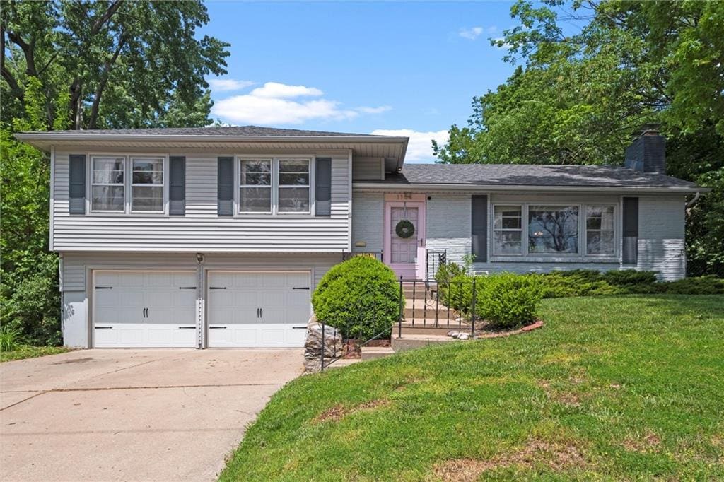 1104 W 89th St, Kansas City, MO 64114 - tri-level home featuring a garage, driveway, a front yard, and a chimney