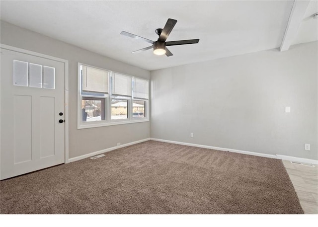 foyer entrance featuring visible vents, a ceiling fan, baseboards, and carpet