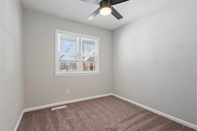 carpeted empty room with ceiling fan, visible vents, and baseboards