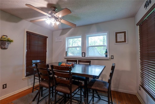 dining space featuring a textured ceiling, baseboards, ceiling fan, and wood finished floors