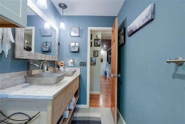 bathroom with baseboards, wood finished floors, and vanity