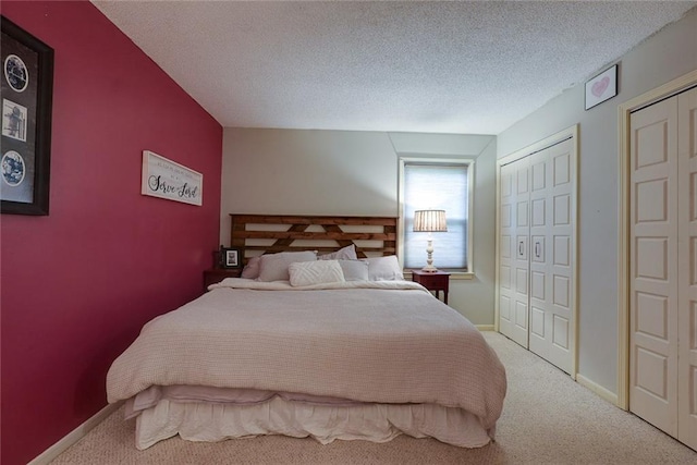 carpeted bedroom with baseboards, a textured ceiling, and multiple closets