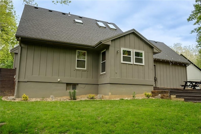 back of house featuring a lawn, a shingled roof, and board and batten siding