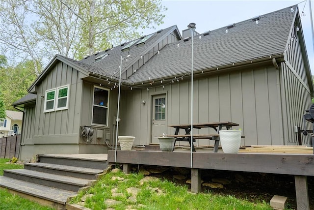 rear view of property featuring a shingled roof, board and batten siding, and a wooden deck