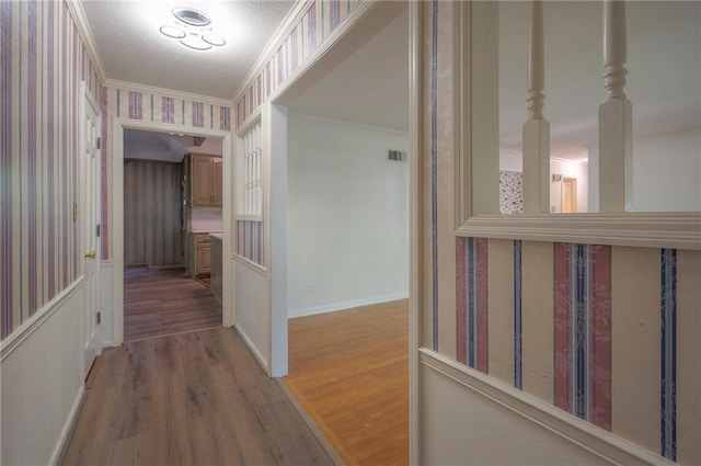 3913 Stonewall Ave, Independence, MO 64055 - hall featuring baseboards, wallpapered walls, wood finished floors, visible vents, and ornamental molding