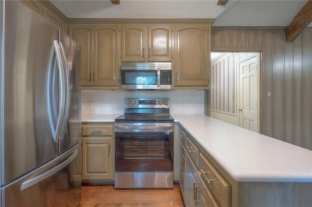 3913 Stonewall Ave, Independence, MO 64055 - kitchen with light countertops, stainless steel appliances, a peninsula, wood finished floors, and backsplash