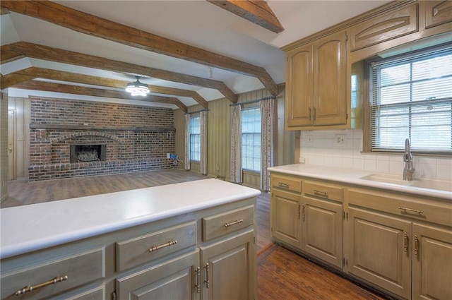3913 Stonewall Ave, Independence, MO 64055 - kitchen with dark wood-style flooring, a brick fireplace, light countertops, tasteful backsplash, and a sink