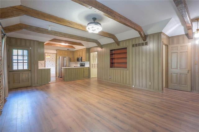 3913 Stonewall Ave, Independence, MO 64055 - unfurnished living room with beam ceiling, wood walls, light wood-style flooring, baseboards, and visible vents
