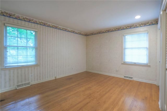 3913 Stonewall Ave, Independence, MO 64055 - spare room featuring visible vents, light wood finished floors, and wallpapered walls