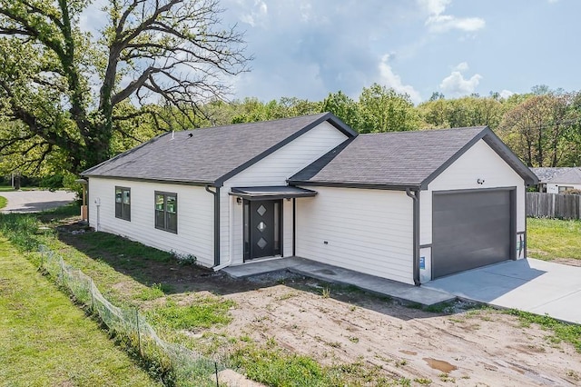 ranch-style home with fence, driveway, roof with shingles, and a garage
