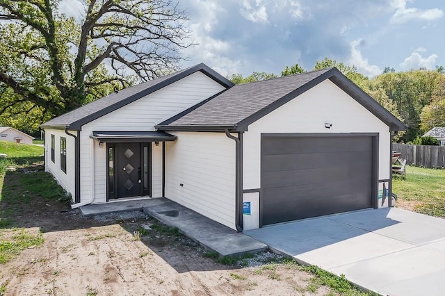 ranch-style home featuring roof with shingles, fence, driveway, and a garage