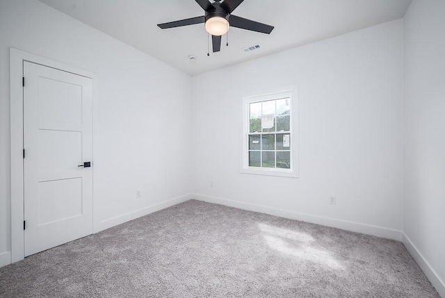 carpeted spare room featuring baseboards, ceiling fan, and visible vents