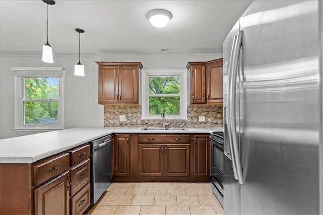 kitchen with appliances with stainless steel finishes, a sink, a peninsula, decorative backsplash, and plenty of natural light
