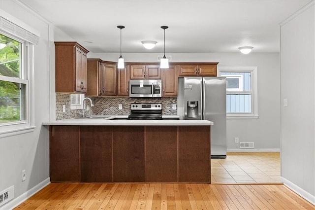 kitchen with stainless steel appliances, a sink, light countertops, and light wood-style floors