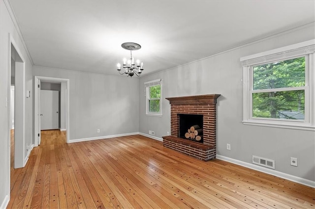 unfurnished living room featuring ornamental molding, a chandelier, light wood finished floors, baseboards, and a fireplace