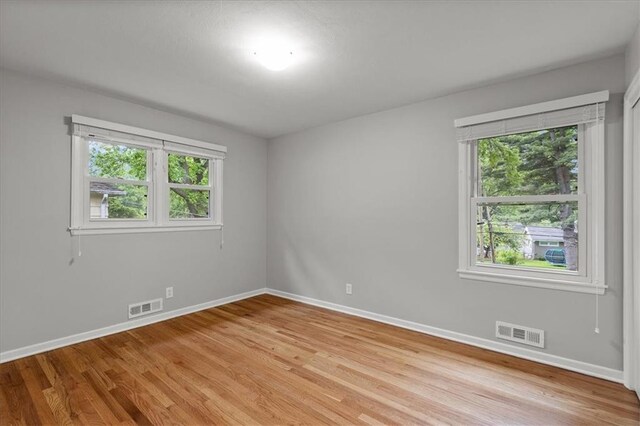 spare room featuring healthy amount of natural light, baseboards, and light wood-type flooring