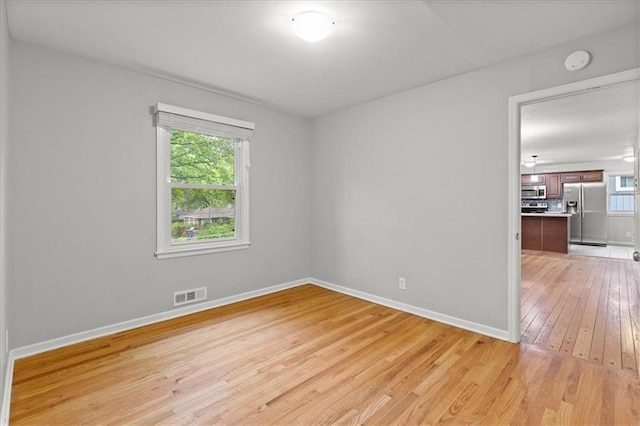 spare room featuring light wood-style floors, a smoke detector, and baseboards