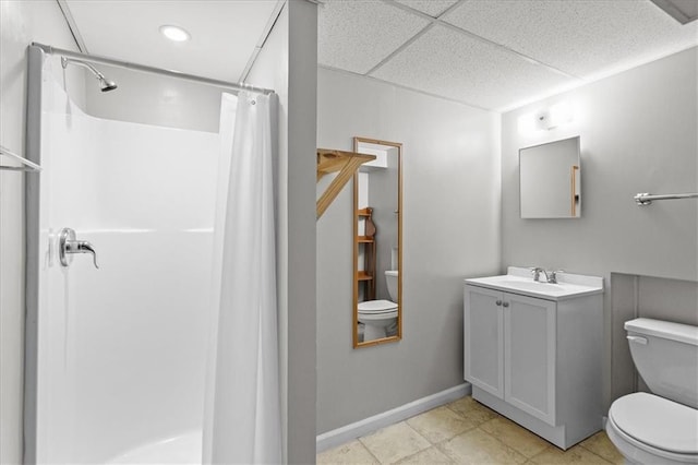 bathroom featuring toilet, a shower with curtain, a paneled ceiling, vanity, and baseboards