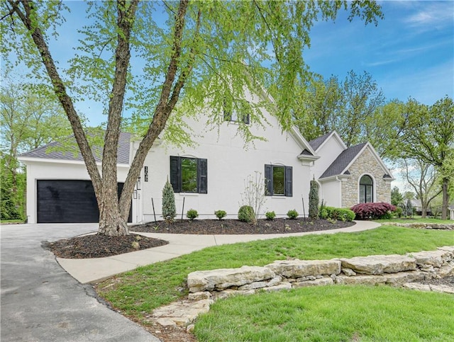 17045 S Highland Ridge Dr, Loch Lloyd, MO 64012 - view of front of home with stone siding, driveway, an attached garage, a front lawn, and stucco siding