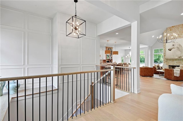 17045 S Highland Ridge Dr, Loch Lloyd, MO 64012 - hall with a chandelier, an upstairs landing, a decorative wall, and light wood-style floors