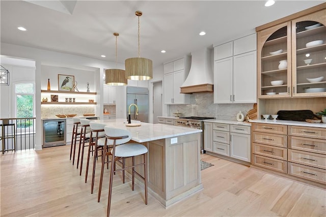 17045 S Highland Ridge Dr, Loch Lloyd, MO 64012 - kitchen with premium range hood, beverage cooler, light wood-style floors, a breakfast bar area, and recessed lighting