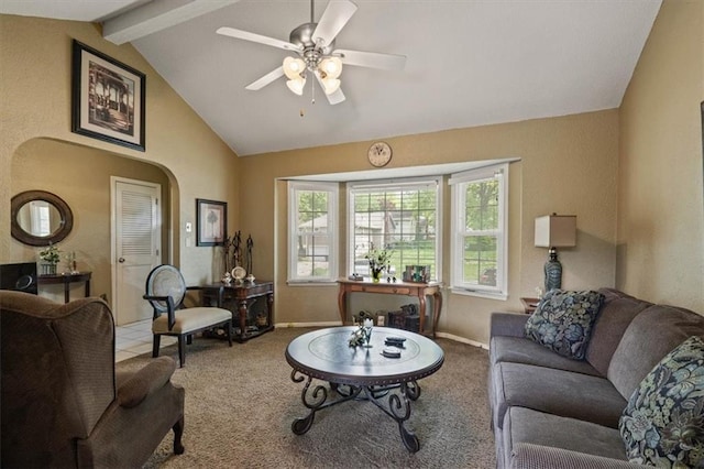 carpeted living room with arched walkways, vaulted ceiling with beams, baseboards, and a ceiling fan