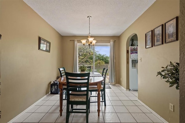 dining space with arched walkways, a textured ceiling, light tile patterned flooring, and a notable chandelier