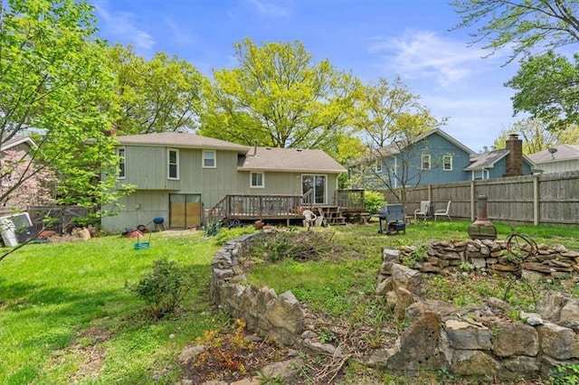 back of property featuring a lawn, a fire pit, fence, and a wooden deck
