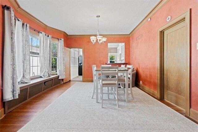 2717 Faraon St, Saint Joseph, MO 64501 - dining area featuring wood finished floors, crown molding, a chandelier, healthy amount of natural light, and baseboards