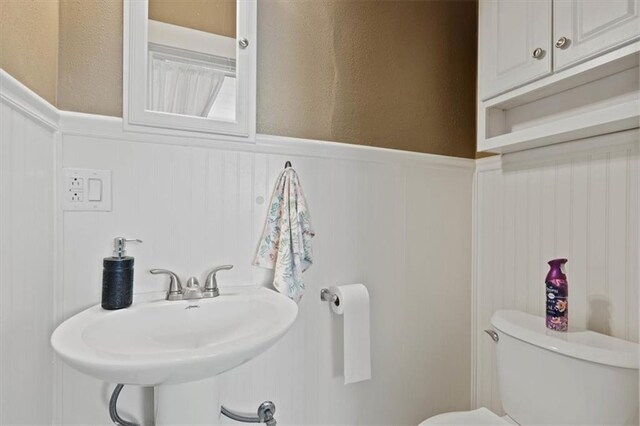 2717 Faraon St, Saint Joseph, MO 64501 - bathroom with a wainscoted wall, toilet, a textured wall, a sink, and a decorative wall