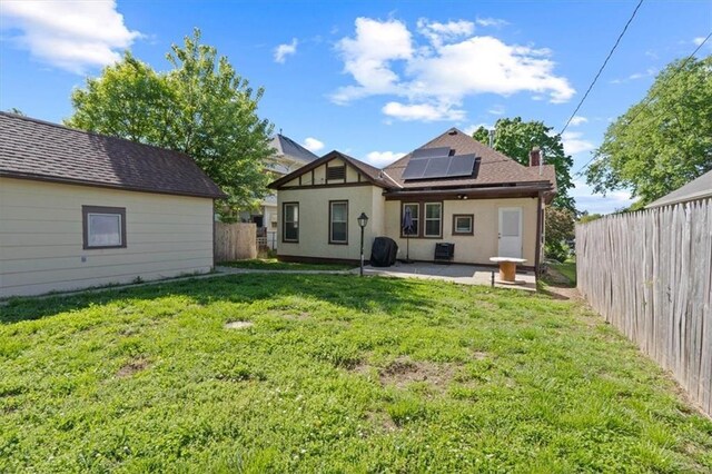 2717 Faraon St, Saint Joseph, MO 64501 - rear view of property featuring a patio, roof mounted solar panels, stucco siding, and a chimney