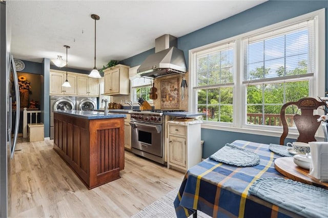 2106 Kasold Dr, Lawrence, KS 66047 - kitchen with a center island with sink, wall chimney range hood, separate washer and dryer, appliances with stainless steel finishes, and a wealth of natural light